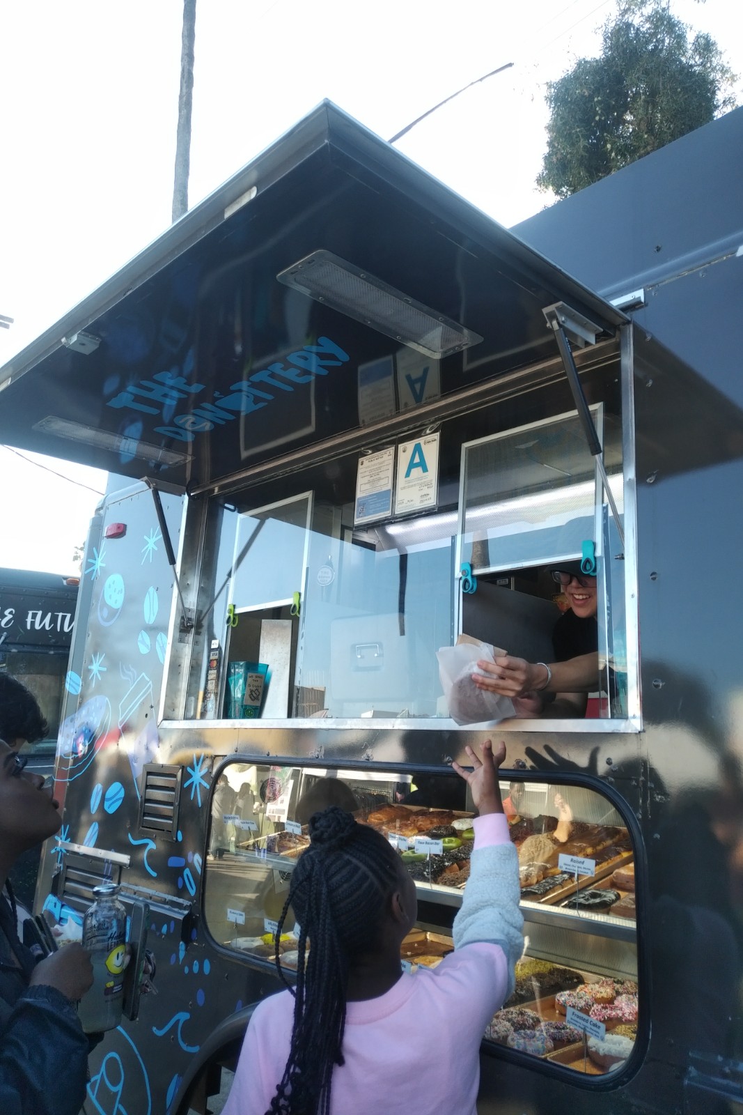 An Employee at the The Donuttery giving a customer their vegan donut!